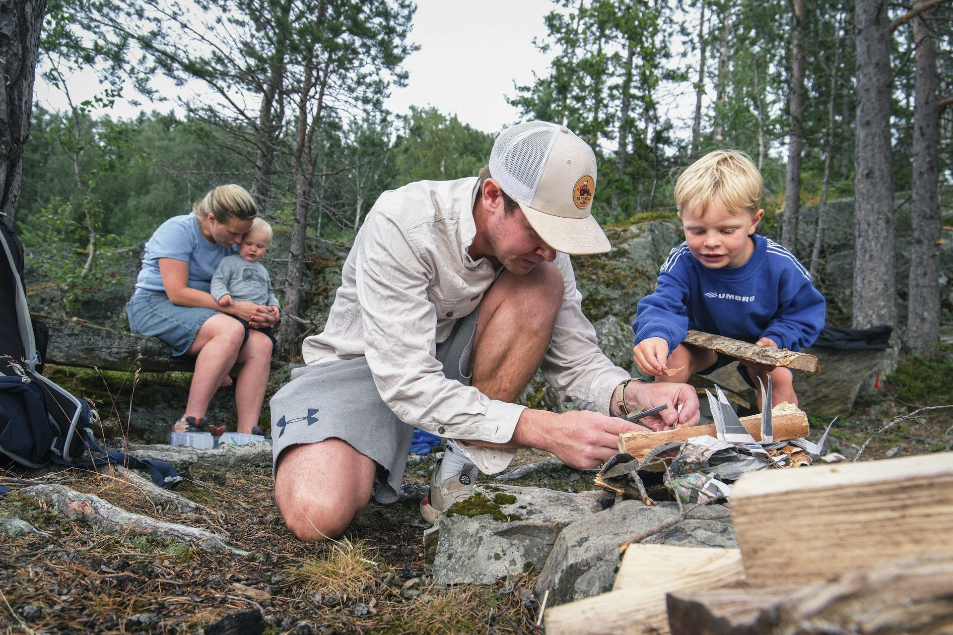 A campfire being lit on the farm, hands tending the kindling in the woods.
